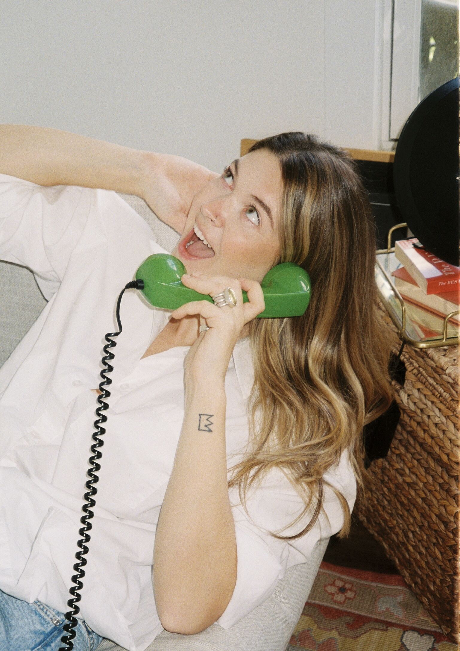 Woman smiling while talking on a retro green phone — playful featured image for blog post on how forecast sales for creative business owners.
