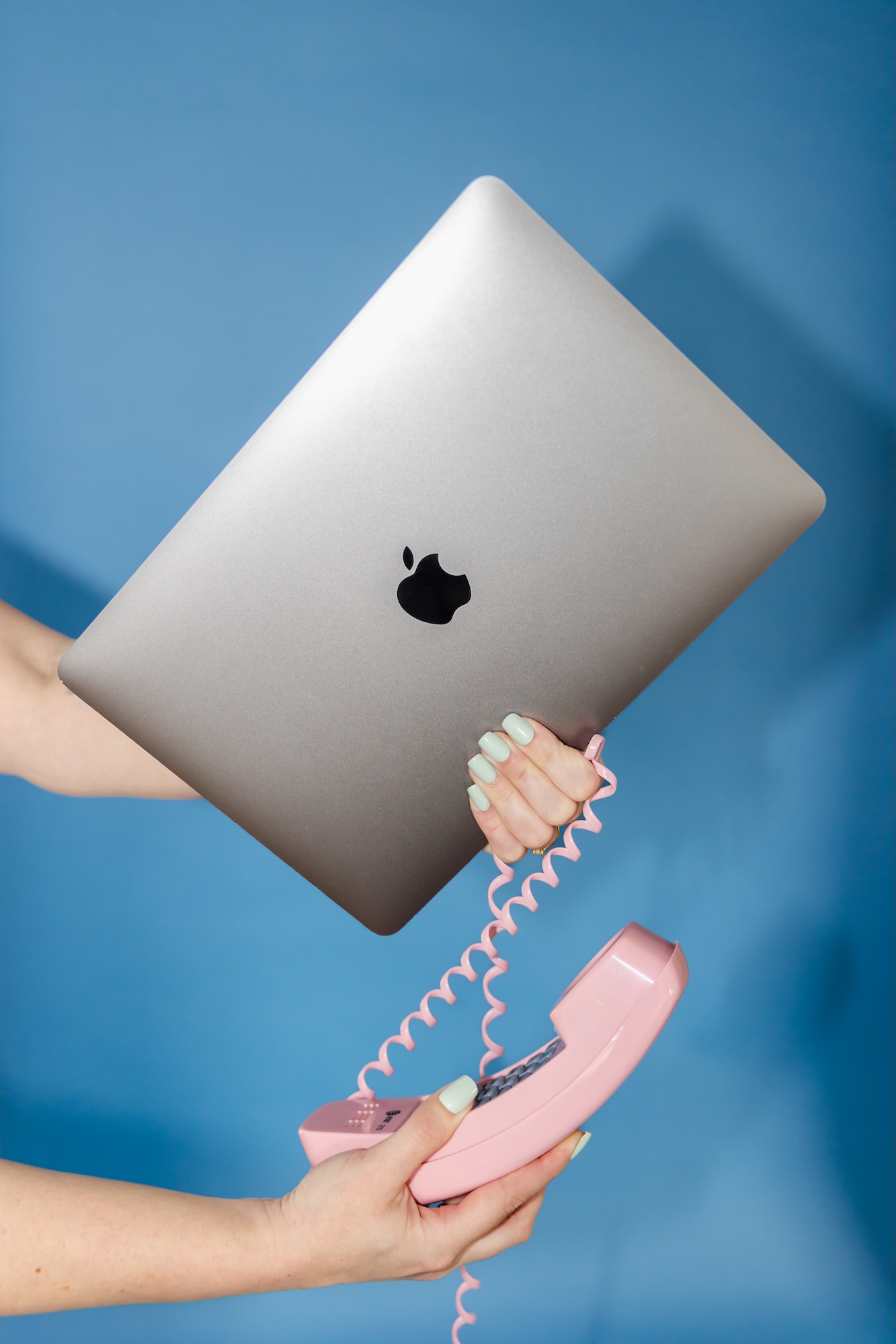 Alexis Jacobson holds a computer and a phone playfully in a metaphor for Maine SEO.